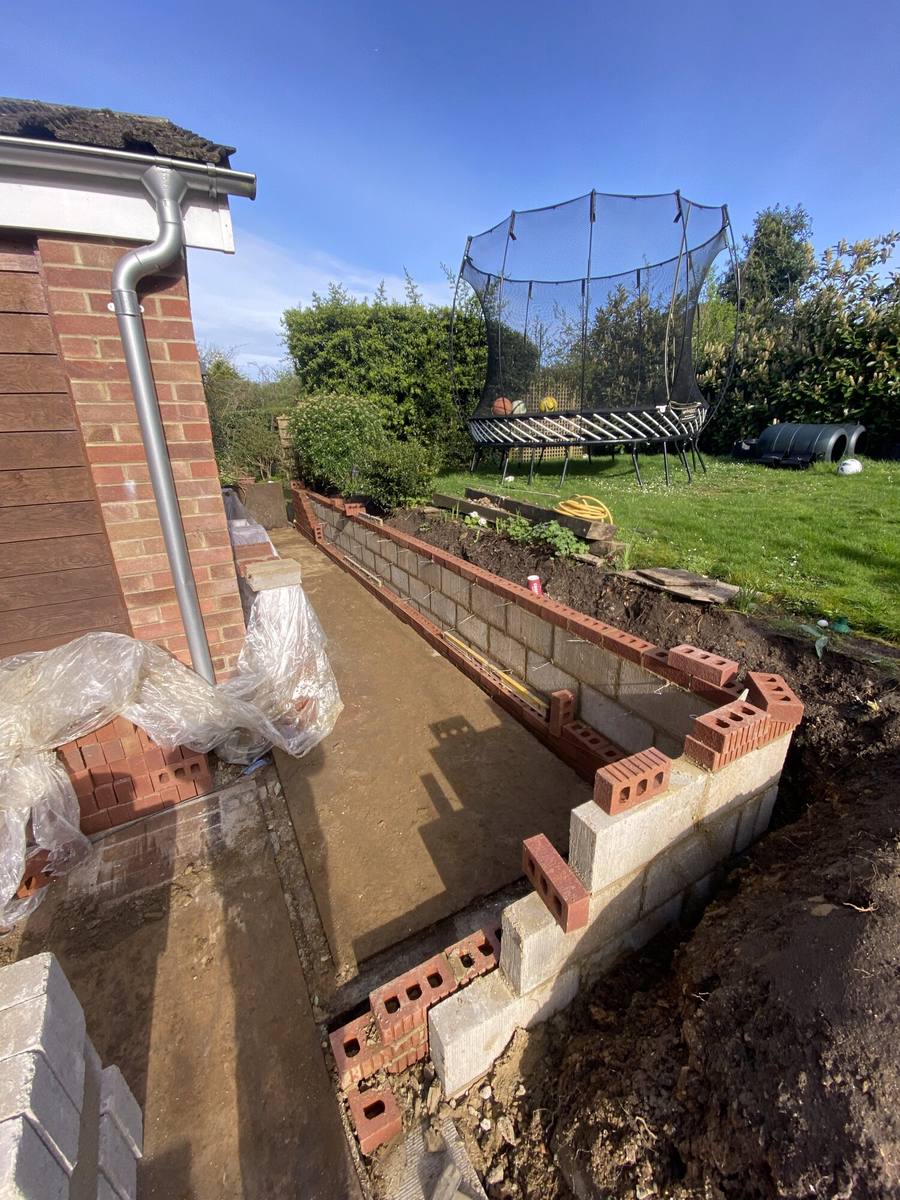 Brick retaining wall under construction along an excavated bank