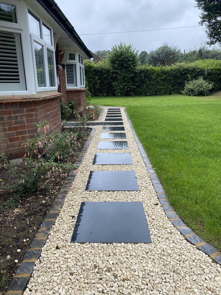 Front garden with rectangular slabs set in gravel leading to a house
