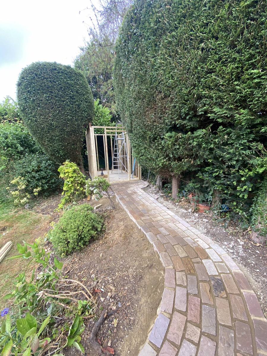 Clipped hedge arch over a brick path leading through a garden