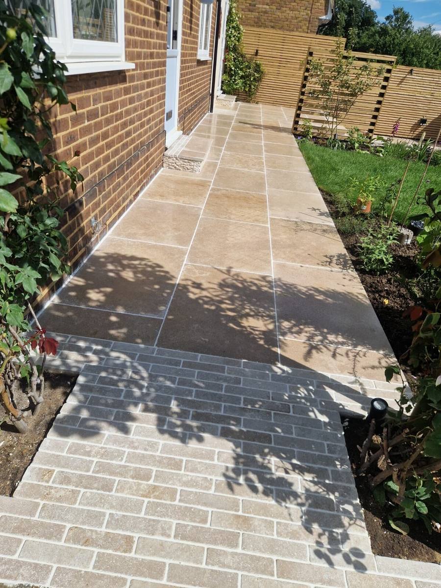 Limestone path along the side of a house with a dark sett border and planted bed
