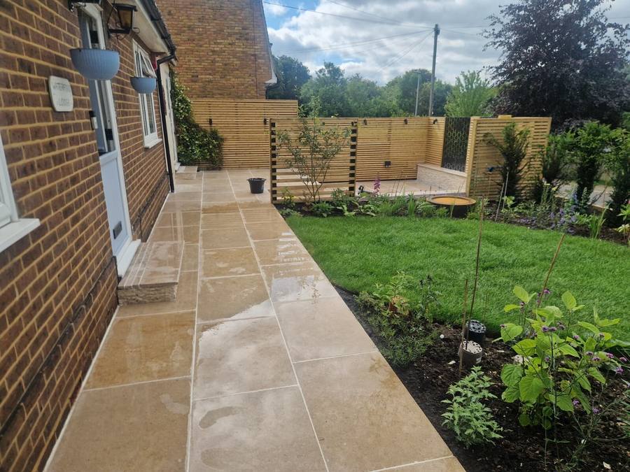Limestone paving beside a brick house with a new lawn and freshly planted borders