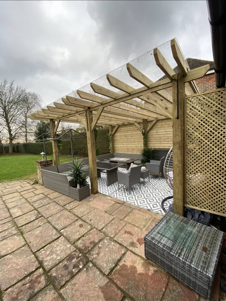 Timber pergola over a paved seating area with sofas and planting