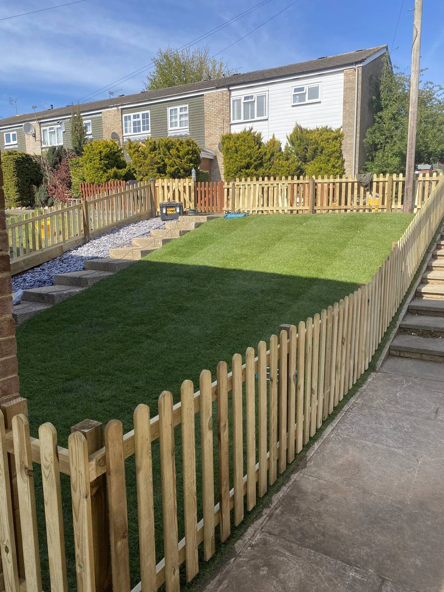 White-tipped picket fence enclosing a small front lawn beside a path