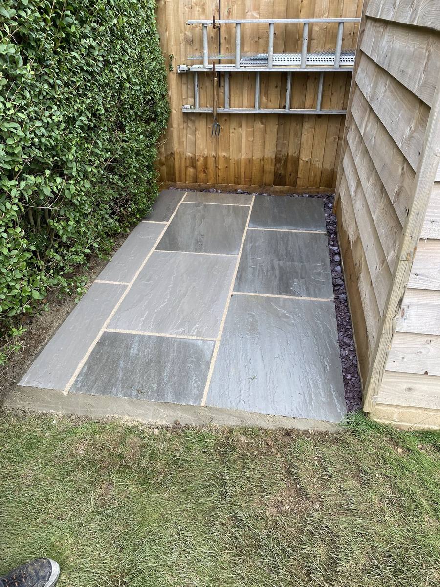 Grey porcelain path running beside a close-boarded fence and lawn