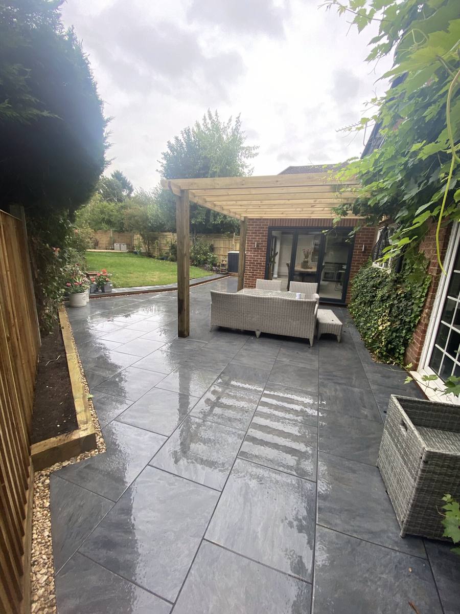 Wet grey porcelain patio with a timber pergola and outdoor sofa