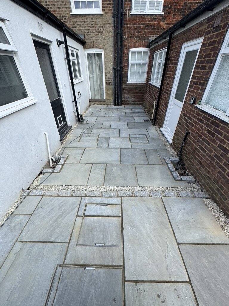 Sandstone paving running along a narrow side return between two houses