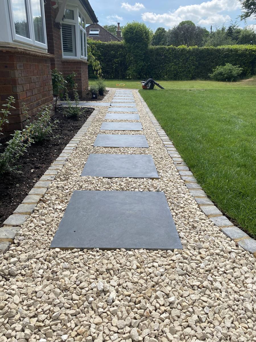 Sawn stone slabs set into gravel forming a path across a lawn